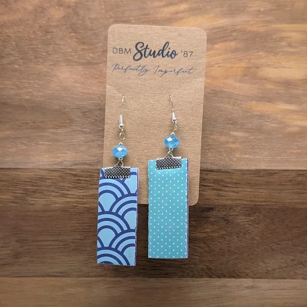 Medium length scrapbook earrings rectangles with purple felt core. Front is Light blue with purple swirls. Back is Light blue polka dots. Light blue/peal beads and pewter-toned metals. Back a